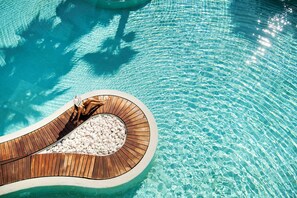 Terraza de madera con una zona de estar circular alrededor de una piscina.