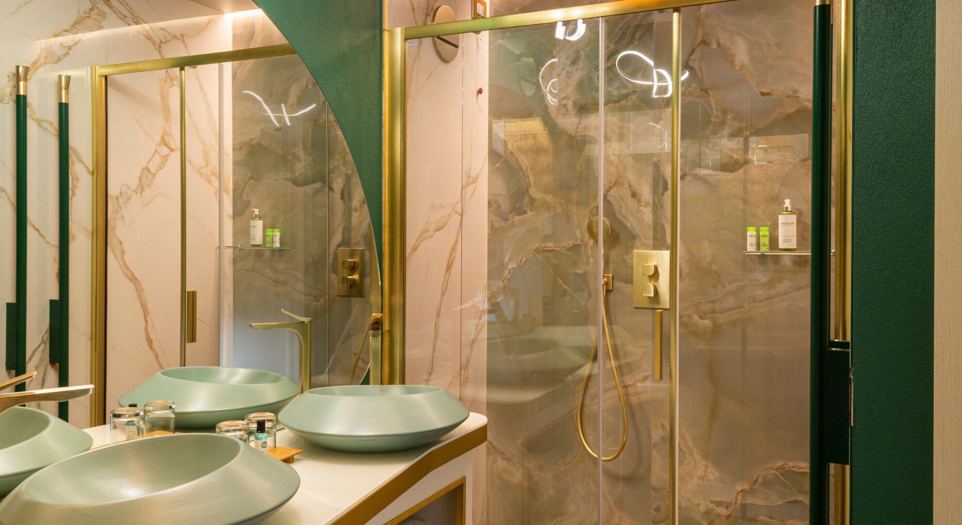 A bathroom with marble walls, a large mirror, and a glass-enclosed shower.