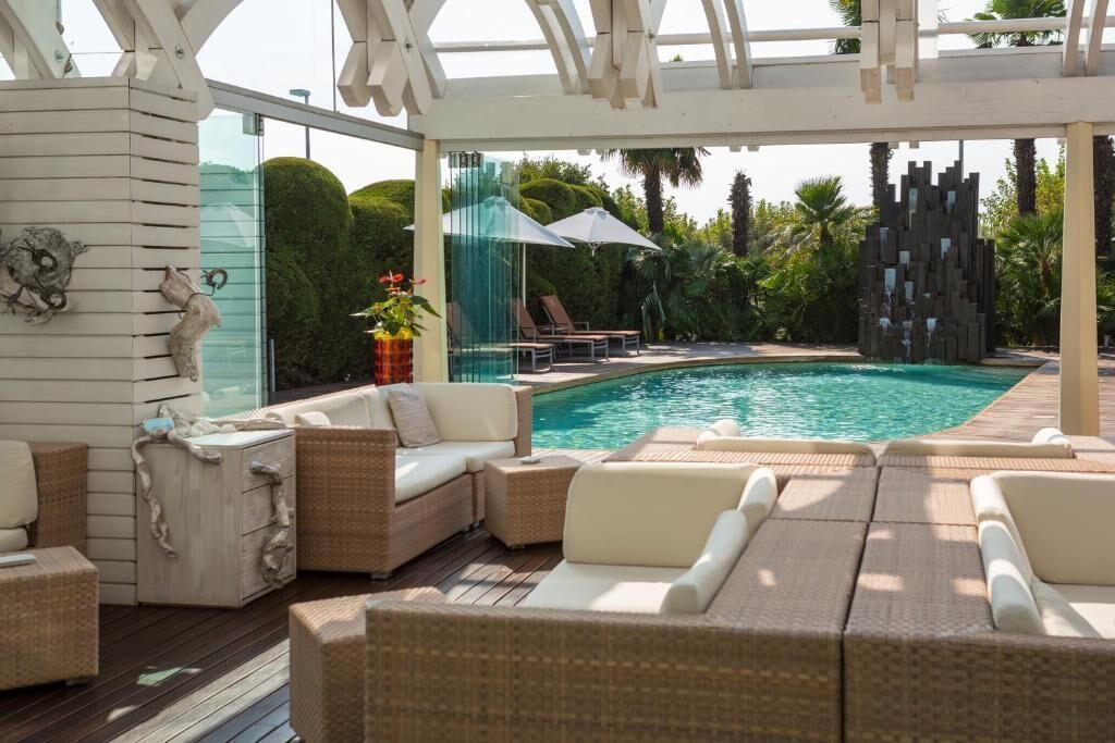An indoor pool area with wicker furniture and a glass wall.