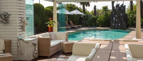 Un área de piscina interior con mobiliario de mimbre y un muro de cristal.