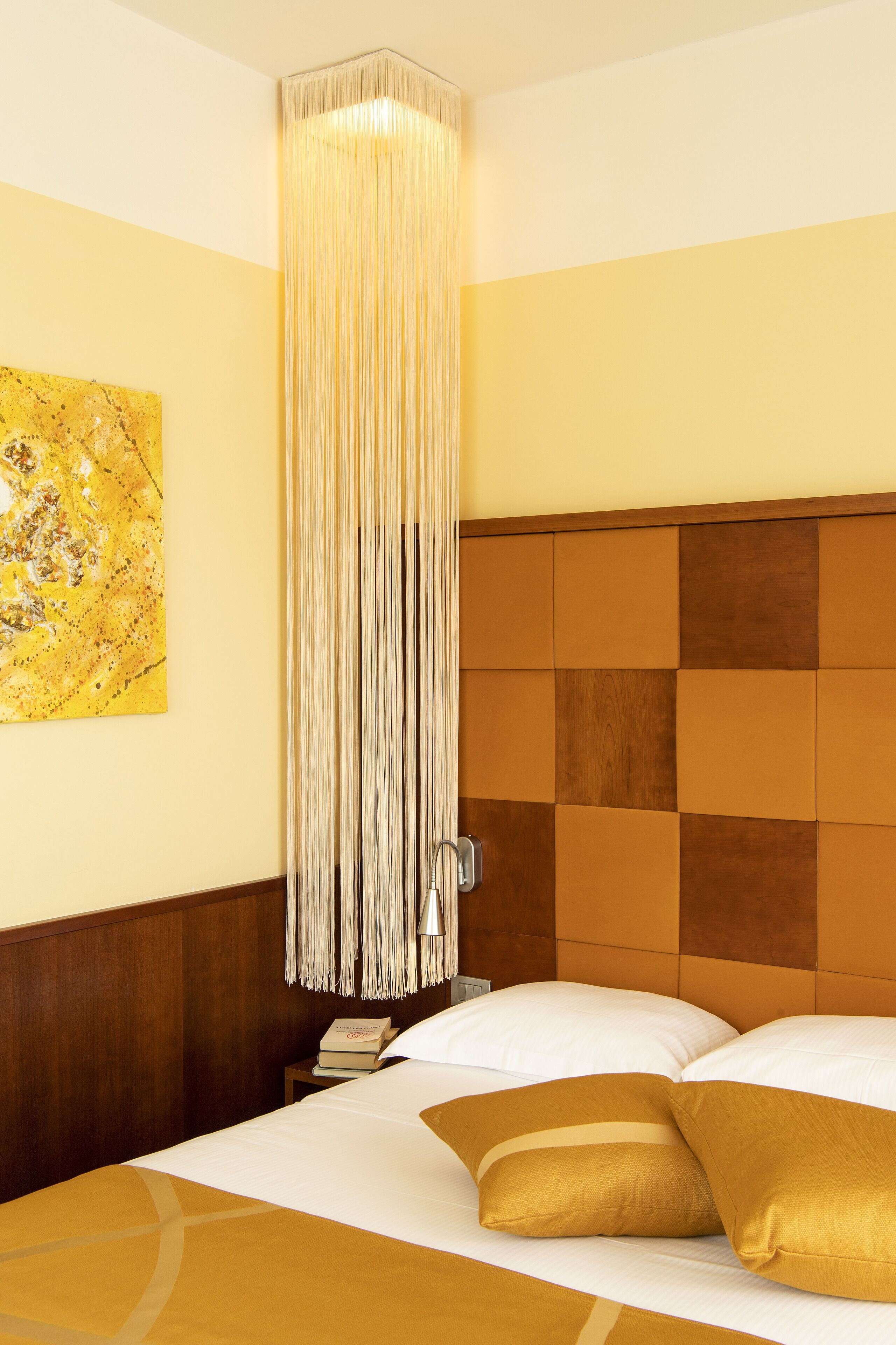 A hotel room with a bed, a nightstand, a lamp, and a painting on the wall.