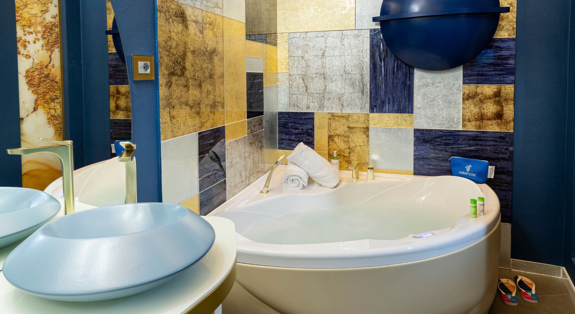 Un baño con bañera, dos lavamanos y una pared azul con diseño de mosaico.