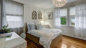 A bedroom with a bed, bedside table, lamp, and a window with curtains.