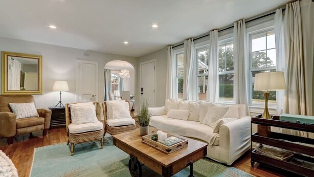 A cozy living room with a sofa, armchairs, a coffee table, and a bookshelf.