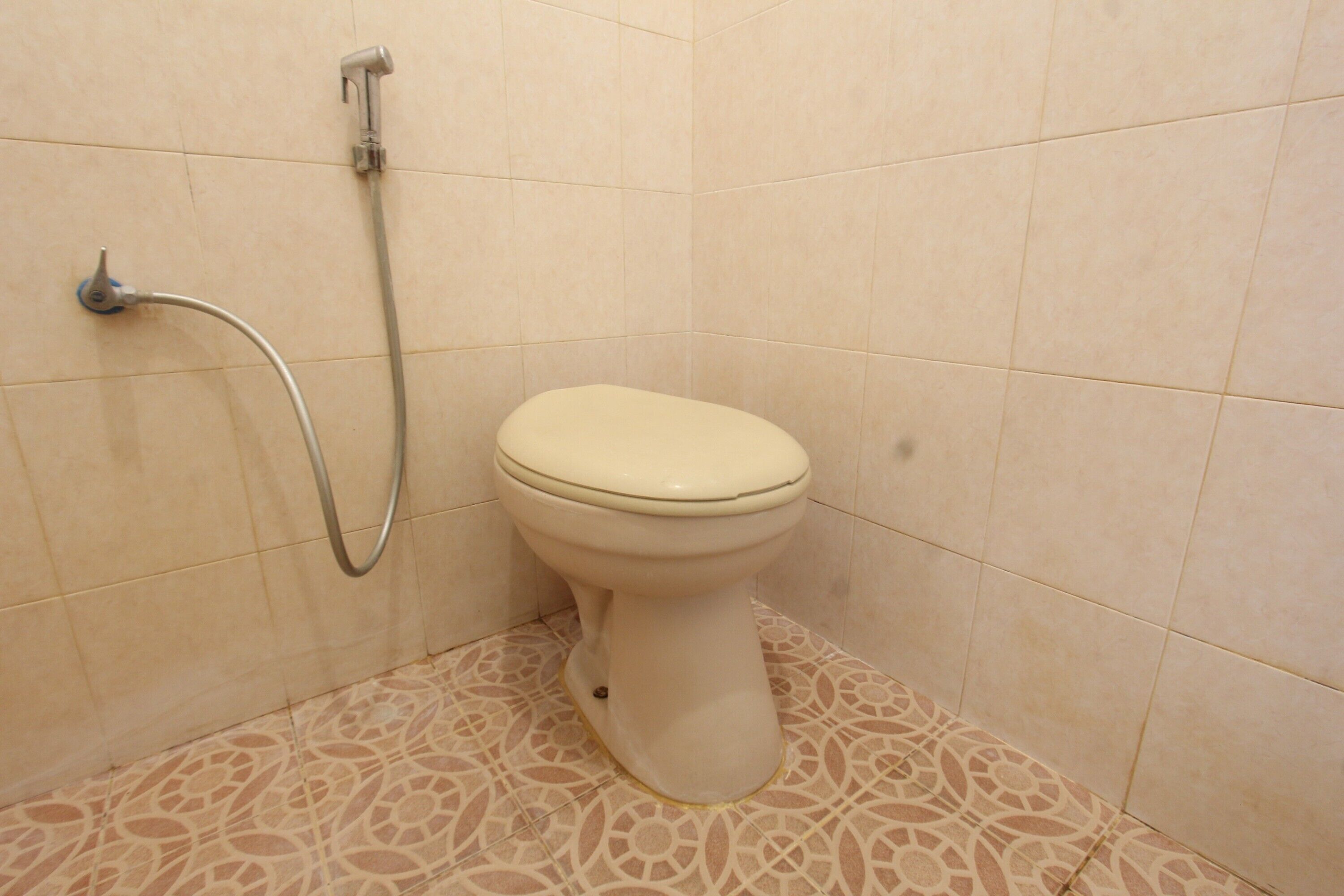 Une salle de bain équipée de toilettes, d’une douche et de carreaux de sol à motifs.