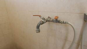 Une douche avec un tuyau en métal et un robinet.