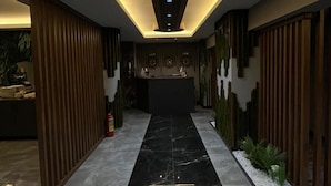 A modern lobby with a black marble floor, wooden paneling, and a central reception desk. - Wonne Boutique Hotel (Ankara)