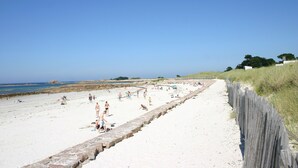 A sandy beach with a wooden fence, people sunbathing and swimming, and a clear blue sky. - Stone house 3km from the beach and close to all amenities. (Penvénan)