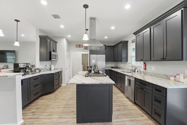 A modern kitchen with dark cabinetry, a central island, and pendant lighting.
