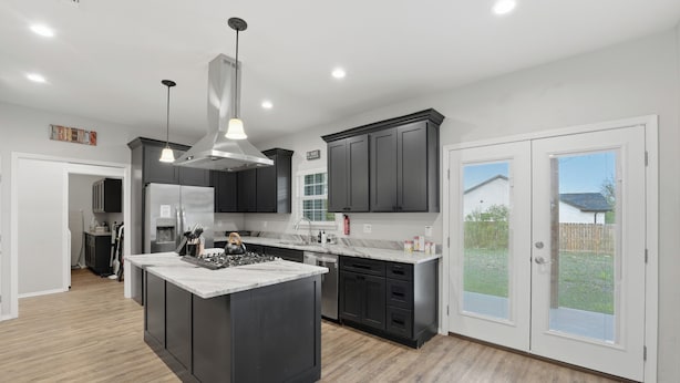 Una cocina moderna con una isla central, muebles oscuros y vistas al exterior.