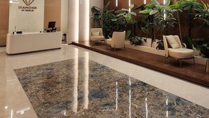 Una zona de recepción moderna con suelo de mármol, mostrador de recepción y varias áreas de estar.