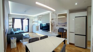 Una sala de estar moderna con sofá, televisión y comedor.