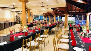 A banquet hall with long tables set for dining, golden chairs, and red napkins. - Rani Beach Hotel (Negombo)
