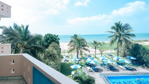 A poolside area with umbrellas, lounge chairs, and a view of the beach and ocean. - Rani Beach Hotel (Negombo)