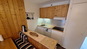 A compact kitchen with wooden cabinets, a built-in dishwasher, and a striped bench. - Appart Duplex / La Plagne, Montchavin / 3 Chambres, 8 Pers / Pied des Pistes (La Plagne-Tarentaise)