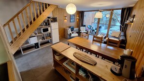 A cozy cabin interior with a wooden staircase, a dining area, kitchen, and a balcony with a view. - Appart Duplex / La Plagne, Montchavin / 3 Chambres, 8 Pers / Pied des Pistes (La Plagne-Tarentaise)