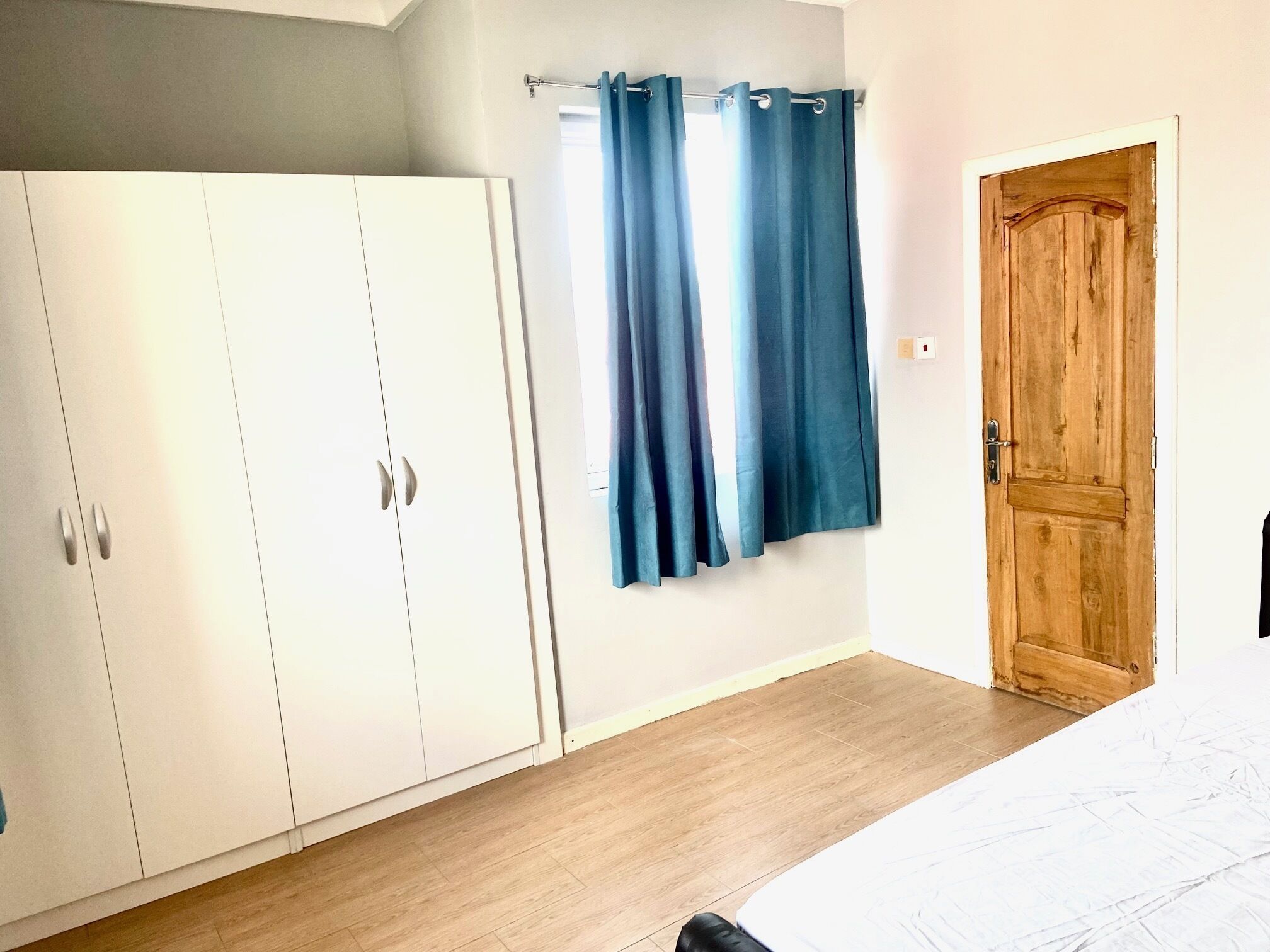 A bedroom with a wooden door, a wardrobe, and a bed.