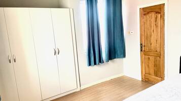 A bedroom with a wooden door, a wardrobe, and a bed.