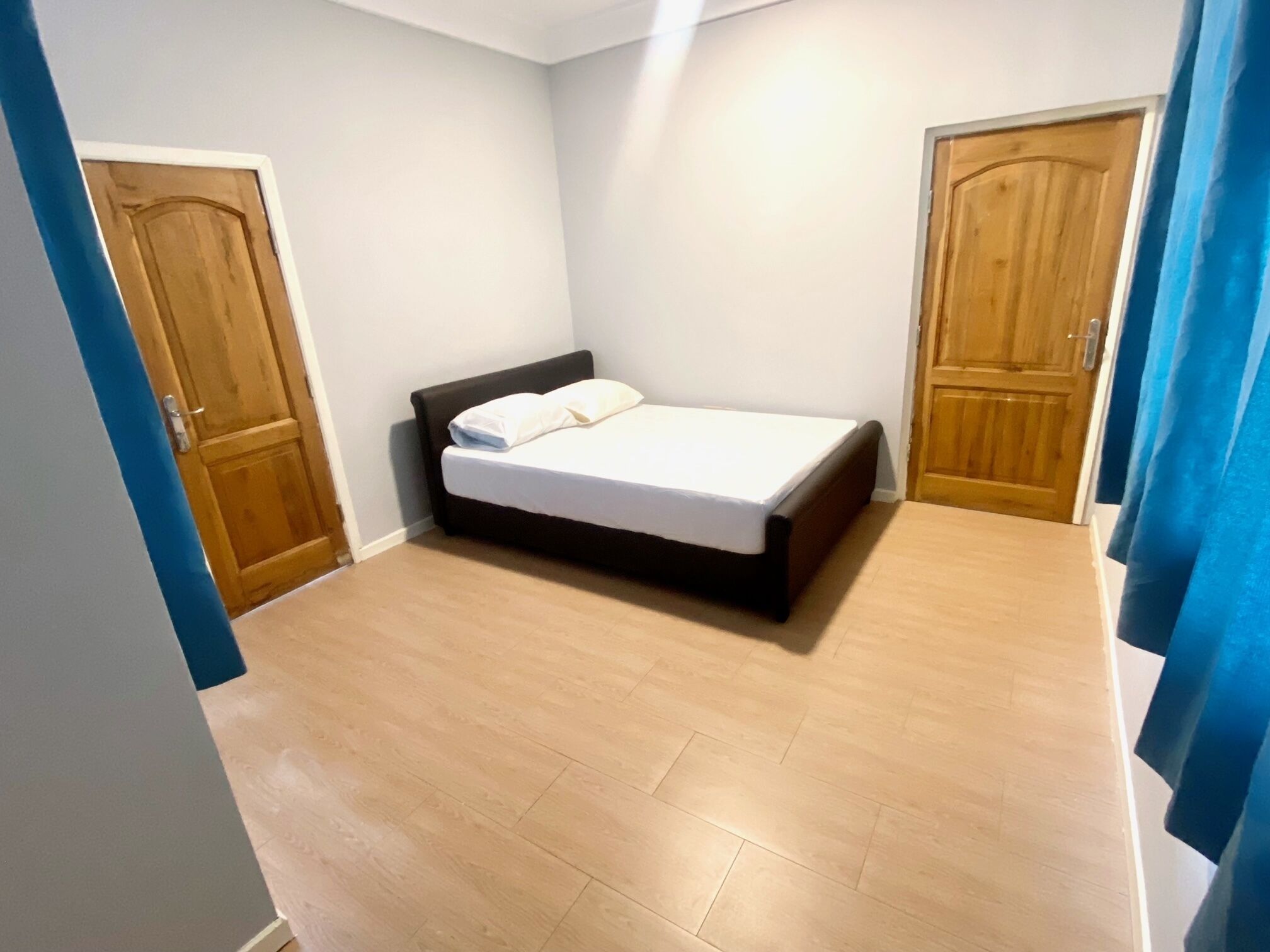 Ein Schlafzimmer mit einem Bett, zwei Holztüren und einem blauen Vorhang.
