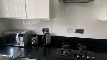 A kitchen with a toaster, kettle, and stove.