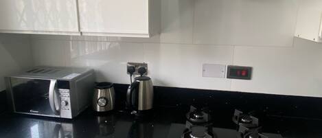 A kitchen with a toaster, kettle, and stove.
