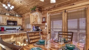 L’intérieur d’un chalet en bois comprend une cuisine, un coin repas et de grandes fenêtres.