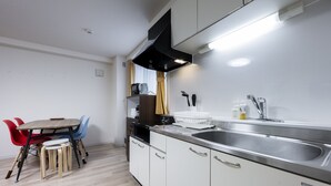 Una cucina moderna con mobili bianchi, un lavello in acciaio inossidabile e un'area pranzo con tavolo in legno e sedie colorate.