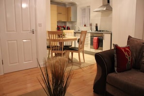 Cozy living space with a dining area and kitchenette, featuring a round table and two chairs, a stove, oven, and sink.