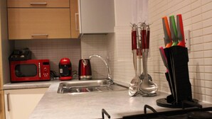 A kitchen with a microwave, coffee maker, sink, and a set of colorful knives on the counter. - Apartment - Sleeps 2 - Parking - Station Close (Dagenham)