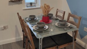 Une table à manger dressée avec des bols, des assiettes et des couverts, entourée de chaises.