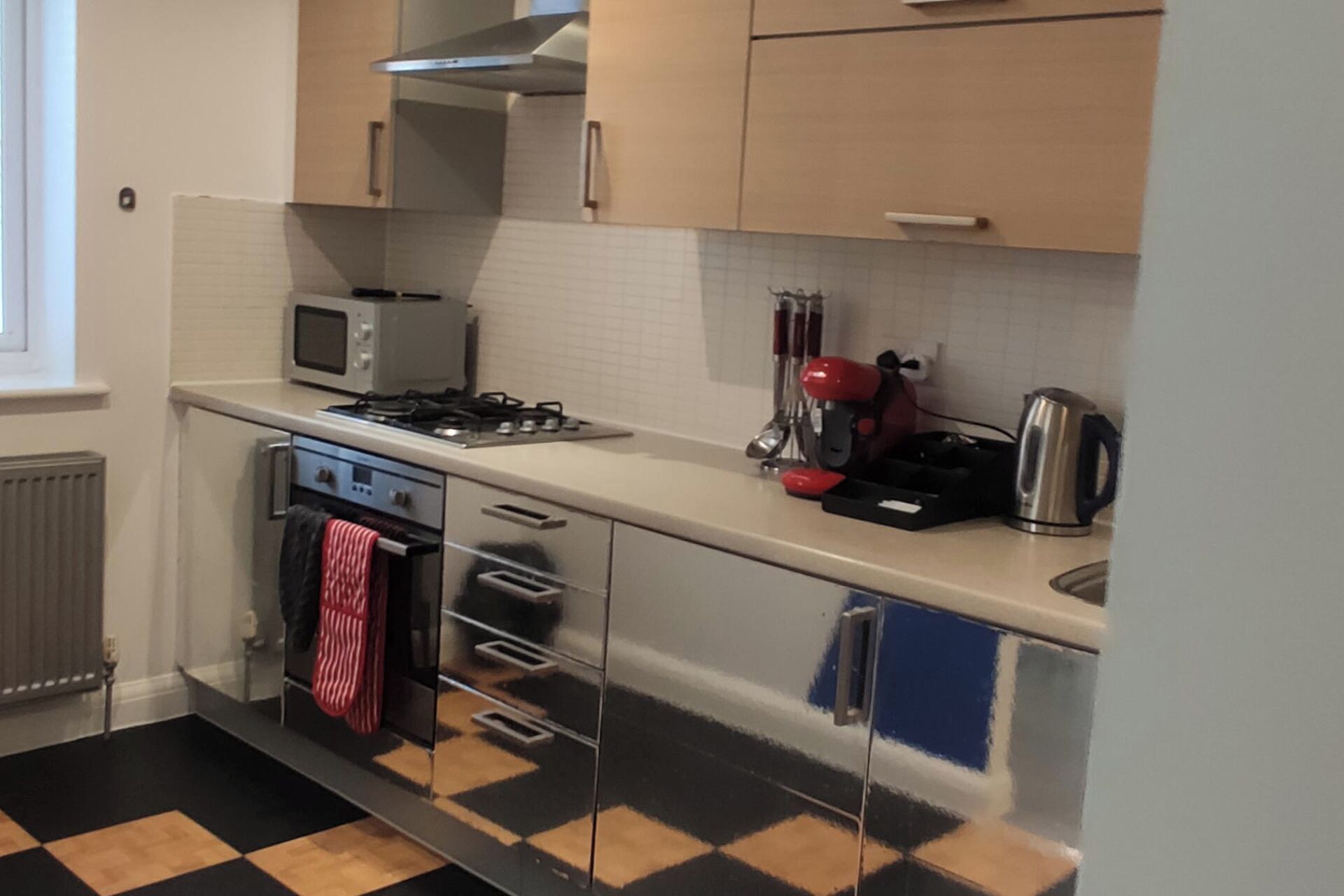 Una cucina accessoriata con microonde, fornello, bollitore e diversi utensili.