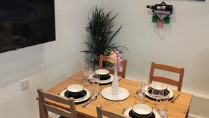 A dining table set with plates, glasses, and cutlery. There is a potted plant and a wall-mounted decoration. - Stunning 2-bed Apartment in London Dagenham (Dagenham)