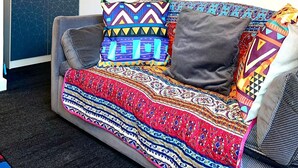 Un canapé agrémenté de coussins à motifs et recouvert d’un plaid coloré.