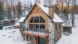 Ein großes, mehrstöckiges Holzhaus mit Balkon und Steinfassade, umgeben von Schnee.