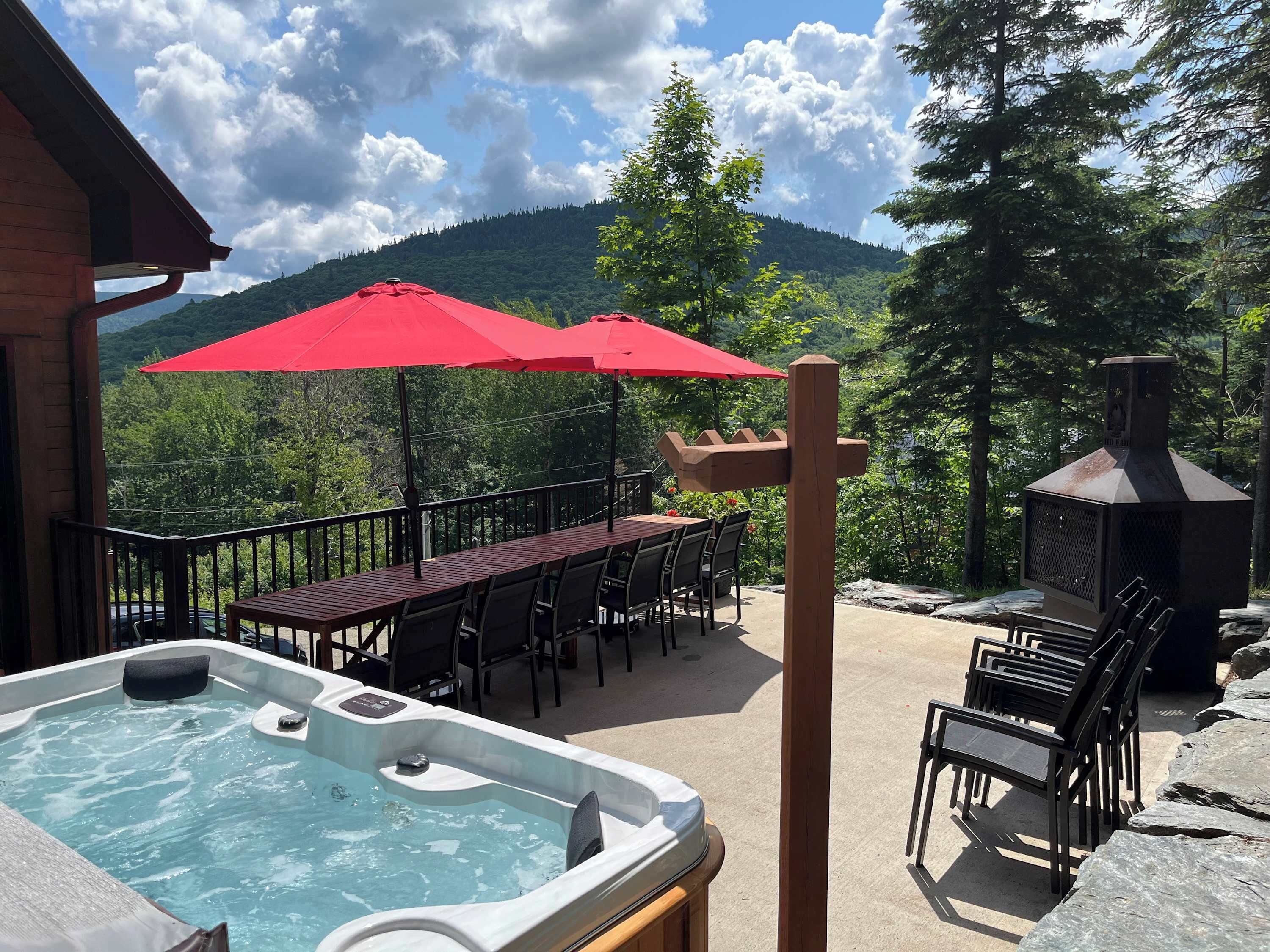 A hot tub, outdoor dining area with chairs, and a barbecue grill.