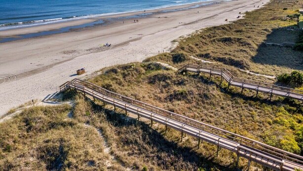 A beach with a wooden boardwalk, sandy beach, and ocean. - TreeHouse Lodge,Walk to Beach,Pet-Friendly 102 (North Myrtle Beach)