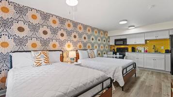 Une chambre d’hôtel avec deux lits, une kitchenette et un mur décoré d’un motif.