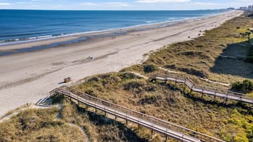 Une plage avec une promenade en bois qui mène au bord de l’eau.