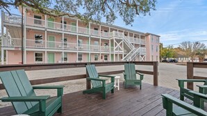A multi-story building with balconies, a wooden deck with chairs and tables, and a clear view of the beach. - TreeHouse Lodge*Walk to Beach*Pet-Friendly (#106) (North Myrtle Beach)