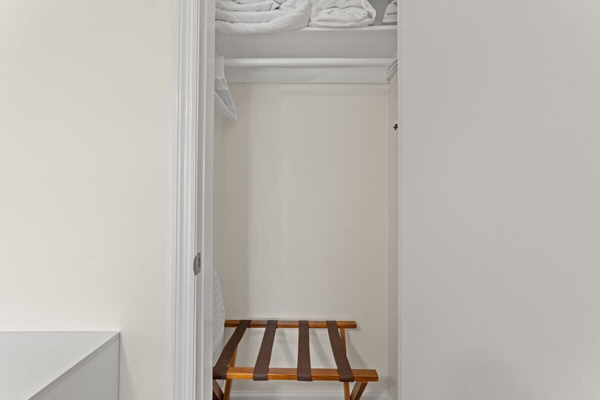 A narrow walk-in closet with a wooden drying rack and neatly folded towels on a shelf.