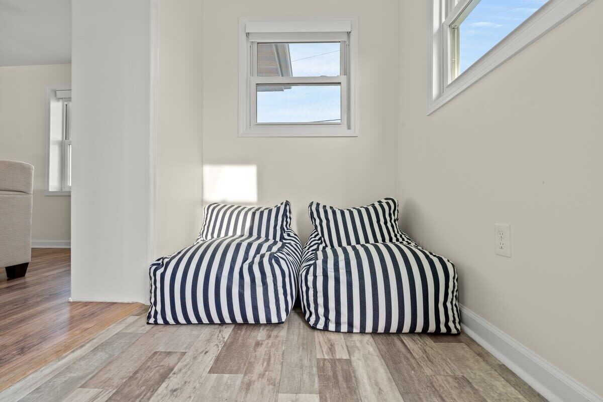 A room with a corner seating area featuring striped bean bag chairs, a window, and a wooden floor.