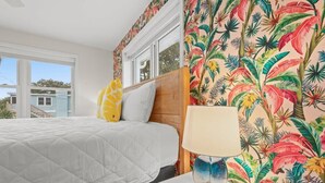 Un dormitorio con una cama, una mesita de noche, una lámpara y una ventana.