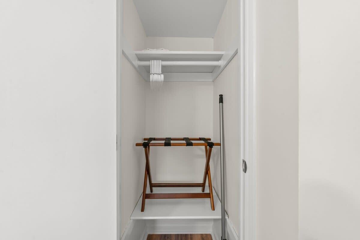 A narrow hallway with a wooden rack and a white shelf.
