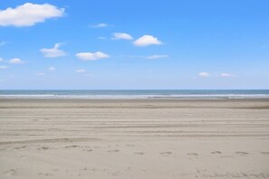 A beach with footprints in the sand and a clear sky.