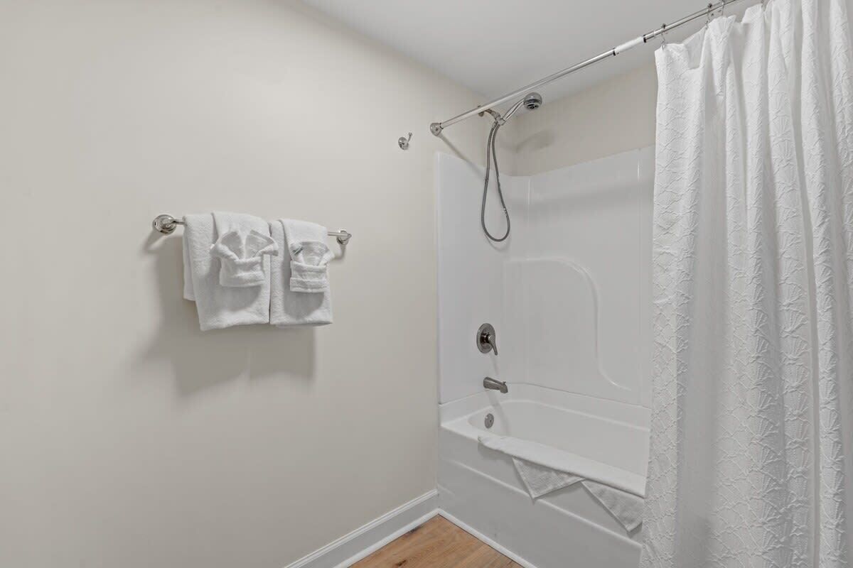 Un baño con bañera, ducha y un perchero con dos toallas.