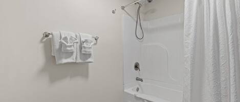 Un baño con bañera, ducha y un perchero con dos toallas.