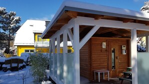 Een houten hut met een veranda, een tafel en een bank.