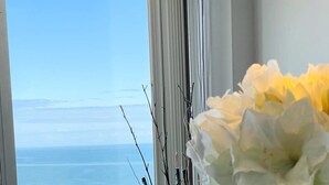 A dining table with a chair, a vase with flowers, and a view of the ocean. - Luxury Large Ocean Front condo with pool, North MB (North Myrtle Beach)