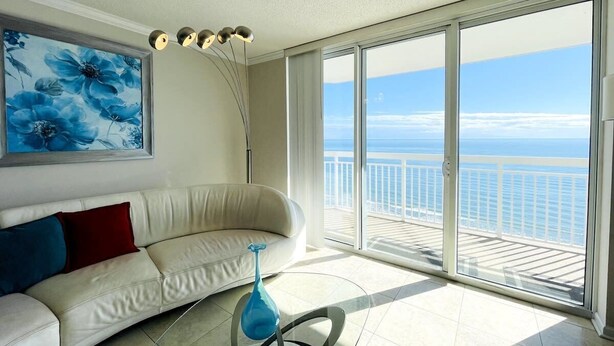 A living room with a white sofa, a blue vase, and a painting of blue flowers. - Luxury Large Ocean Front condo with pool, North MB (North Myrtle Beach)