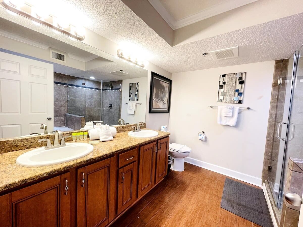 A bathroom with two sinks, a toilet, a shower, and a large mirror.
